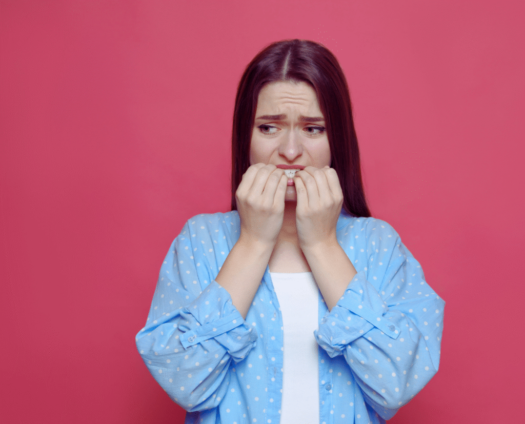 A young woman looking anxious and biting her nails, illustrating how to calm anxiety through effective techniques.