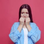 A young woman looking anxious and biting her nails, illustrating how to calm anxiety through effective techniques.