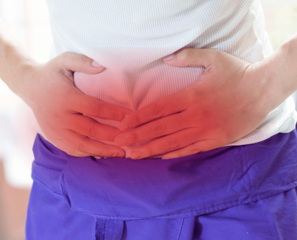 Person holding their upper abdomen with discomfort, illustrating common hiatal hernia symptoms such as pain and pressure.