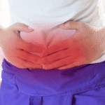 Person holding their upper abdomen with discomfort, illustrating common hiatal hernia symptoms such as pain and pressure.