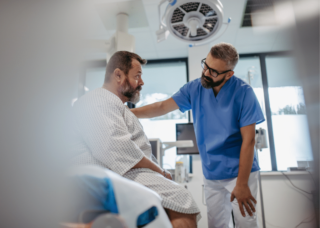 Male doctor reassuring a patient in a hospital gown during a pre-surgery consultation for gastric sleeve abroad.